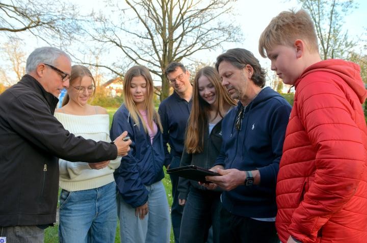 Jugendliche und Erwachsene schauen auf Handys und ein Tablet
